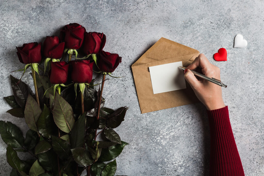 une photo d'une lettre d'amour écrite à la main, accompagnée d'une rose rouge, dans une ambiance chaleureuse et intime